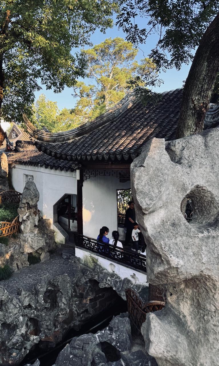 Classical Suzhou garden with white walls, a stone moon gate and a quiet pond